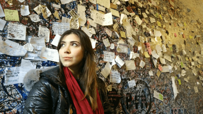 Mulher sentada em frente a uma parede na Casa de Julieta em Verona