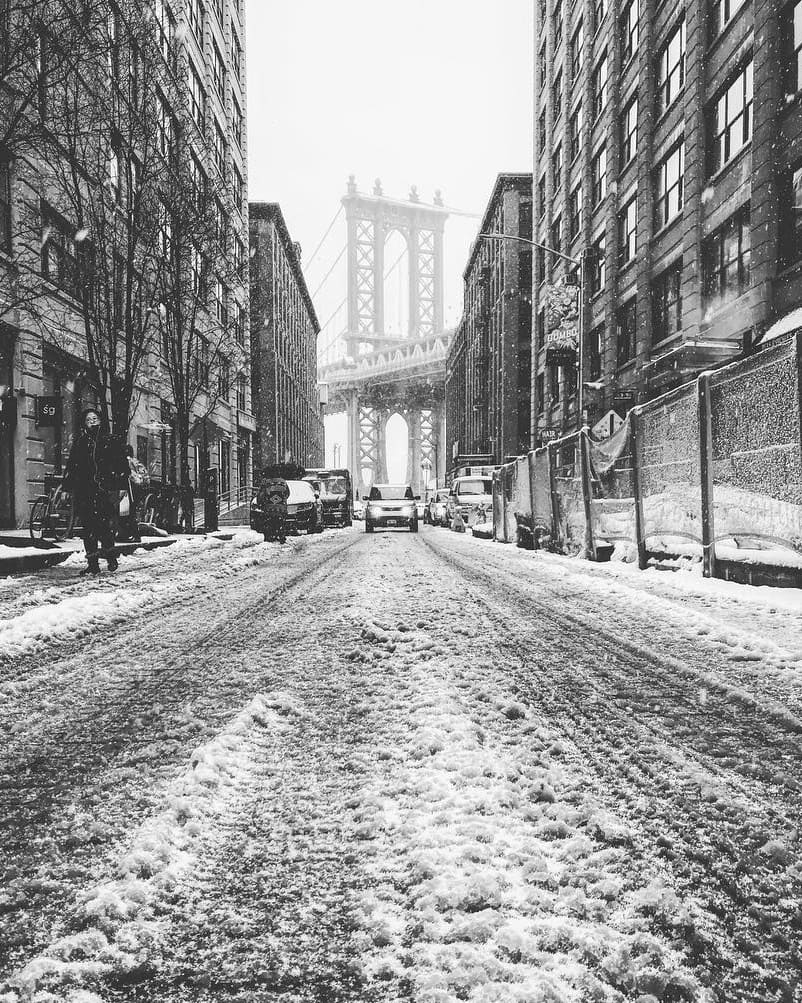 Foto em preto e branco de Nova York no inverno, com neve e a ponte do Brooklyn ao fundo