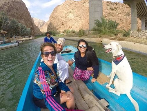 Duas mulheres, dois homens e um cachorro em um barco em Wadi Shab, no Omã