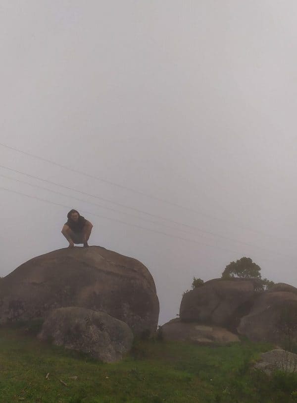 Foto no topo da Pedra da Macela, com homem em cima de uma pedra e muita neblina