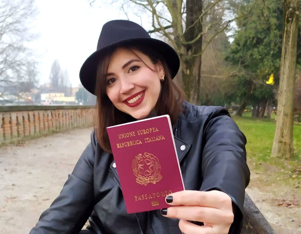 Mulher de chapéu segurando o passaporte italiano, cidadania italiana