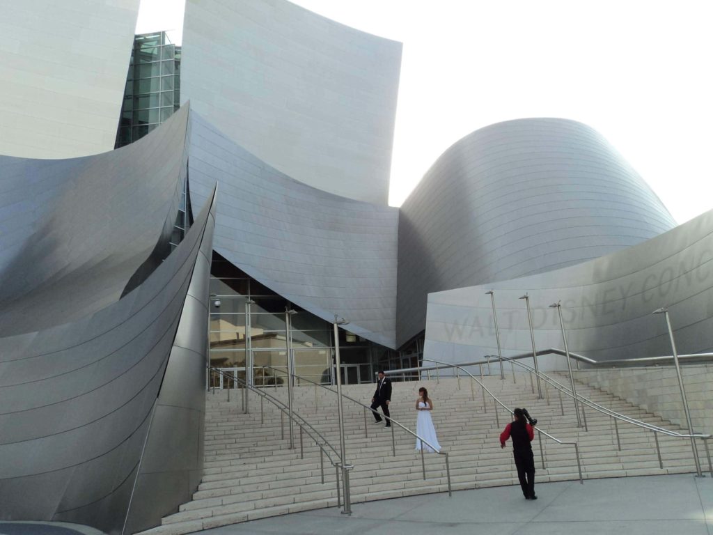 Fachada do Walt Disney Concert Hall em Los Angeles,com um casal de noivos e um fotógrafo nas escadas